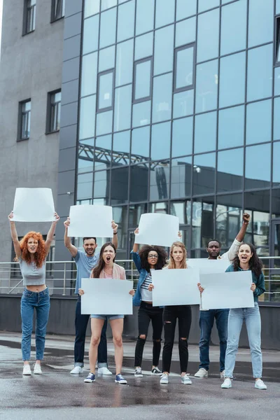 Emotional multicultural group of people with blank placards near building — Stock Photo