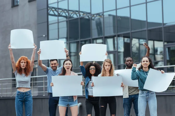 Емоційні мультикультурні люди стоять з порожніми плакатами біля будівлі — стокове фото