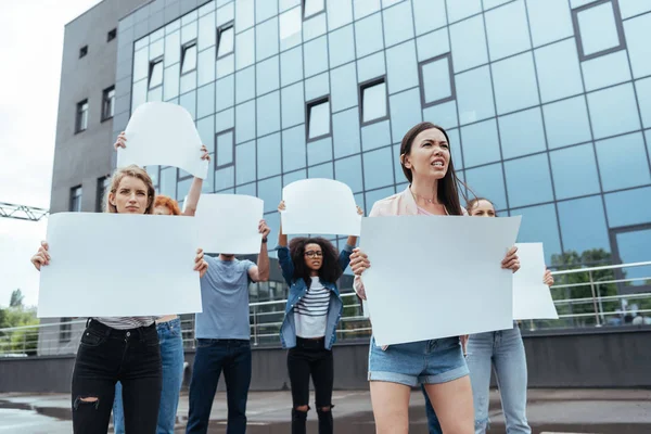 Donne multiculturali e uomo in piedi con cartelli bianchi vicino all'edificio — Foto stock