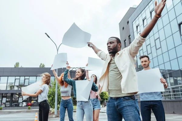 Selektiver Fokus eines afrikanisch-amerikanischen Mannes, der in der Nähe von Mädchen und Männern auf der Straße gestikuliert — Stockfoto