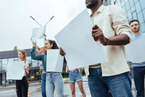 Vista recortada de hombre afroamericano sosteniendo vacía amplia cerca de las niñas y el hombre en la calle - foto de stock