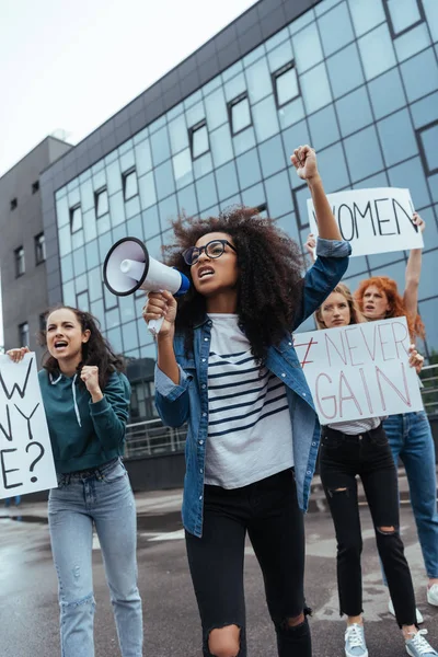Selective focus of emotional african american girl gesturing while holding megaphone near girls on meeting — Stock Photo