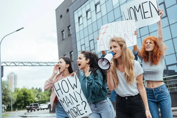 Селективное внимание девушки, держащей мегафон и кричащей рядом с мультикультурными женщинами на встрече — стоковое фото