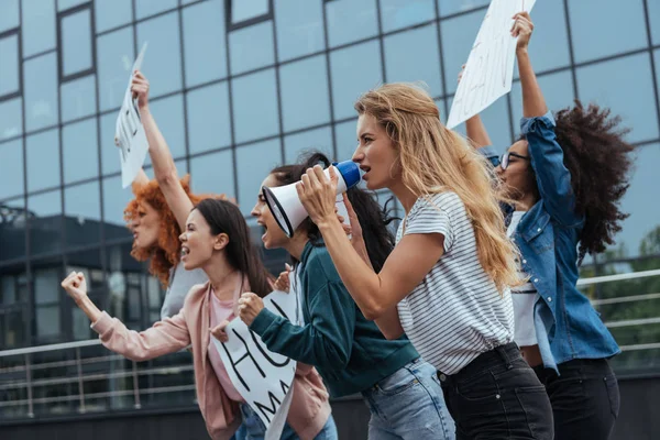 Focalizzazione selettiva di ragazza con megafono vicino a donne multiculturali che tengono cartelli sull'incontro — Foto stock