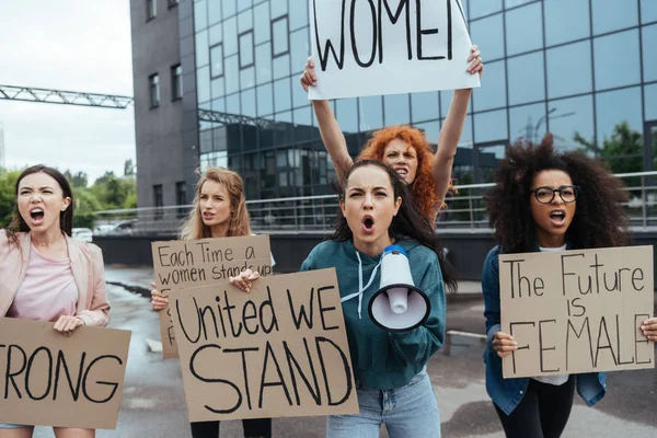 Enfoque selectivo de las mujeres emocionales multiculturales con pancartas en el encuentro - foto de stock