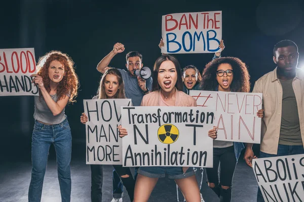 Emotional multicultural men and women holding placards with letters and screaming on black — Stock Photo