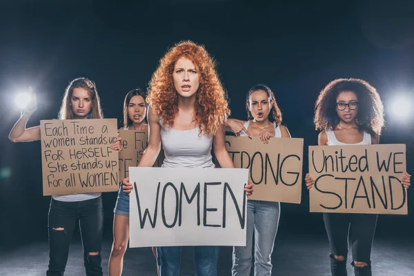 Привлекательные мультикультурные девушки стоят и держат плакаты с надписью на черном — стоковое фото