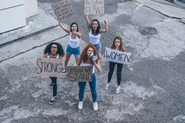 Vista aérea de chicas multiculturales sosteniendo pancartas y gritando afuera - foto de stock