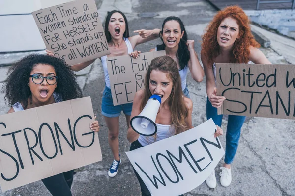 Hermosas chicas multiculturales sosteniendo pancartas y gritando afuera - foto de stock