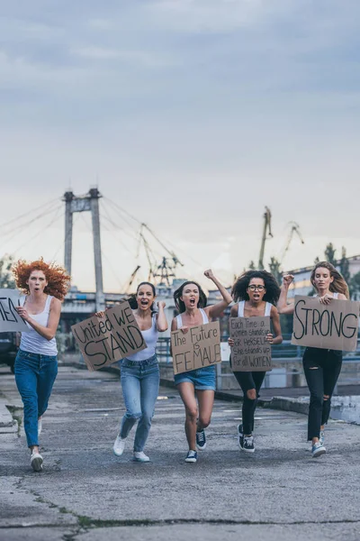 Donne multiculturali che tengono cartelli e corrono fuori — Foto stock