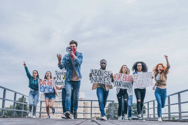 Personas emocionales multiculturales con letras en carteles corriendo afuera - foto de stock