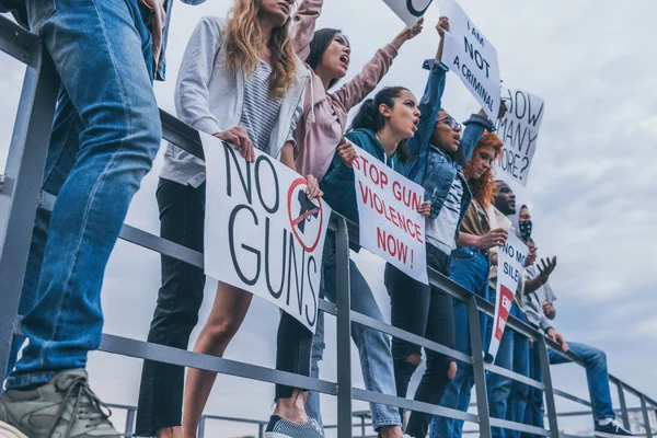 Vista recortada de personas multiculturales con letras en carteles gritando cerca del río - foto de stock