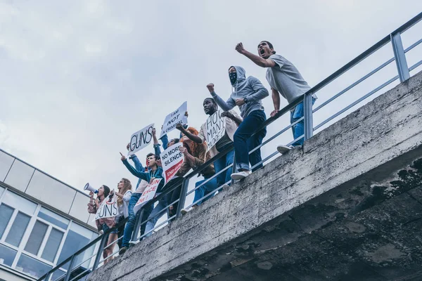 Vista de ángulo bajo de personas multiculturales gritando y haciendo gestos mientras sostiene pancartas - foto de stock