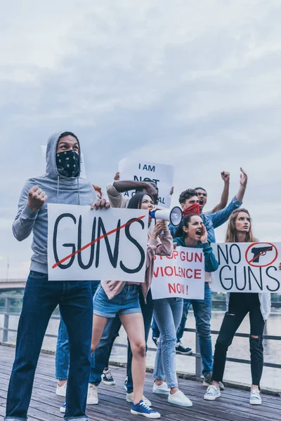 Grupo multicultural de personas que sostienen pancartas mientras hacen gestos durante la protesta - foto de stock