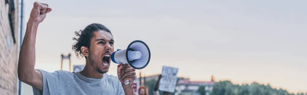 Panoramic shot of african american man screaming while holding megaphone — Stock Photo