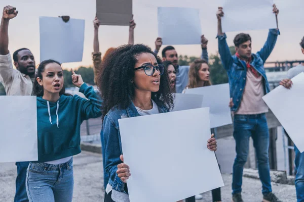 Selective focus of emotional multicultural girls holding blank placards — Stock Photo
