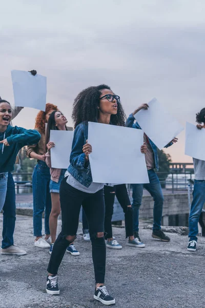 Chicas emocionales multiculturales gritando y sosteniendo pancartas en blanco - foto de stock