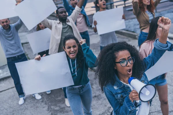 Meninas multiculturais emocionais gritando e segurando cartazes em branco durante o protesto — Fotografia de Stock