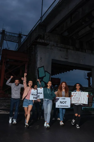 Эмоциональная группа мультикультурных людей, держащих плакаты вечером — стоковое фото