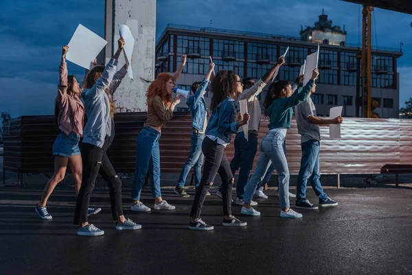 Emotional young multicultural people walking with blank placards — Stock Photo