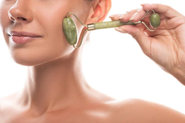 Cropped view of naked young woman using facial jade roller and smiling isolated on white — Stock Photo