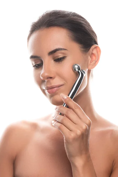 Naked young woman using facial massager with gently smile isolated on white — Stock Photo