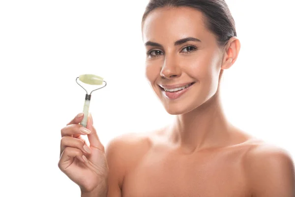 Naked young woman holding facial jade roller and smiling isolated on white — Stock Photo