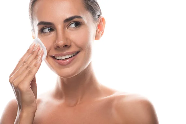 Sorridente giovane donna nuda utilizzando batuffolo di cotone e distogliendo lo sguardo isolato sul bianco — Foto stock