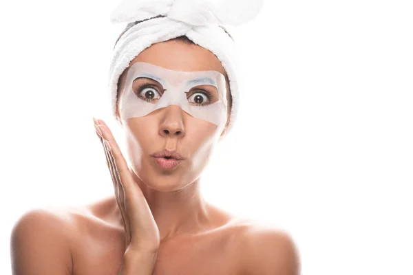 Vista frontale della giovane donna nuda scioccata in fascia di capelli cosmetici con maschera facciale isolata su bianco — Foto stock