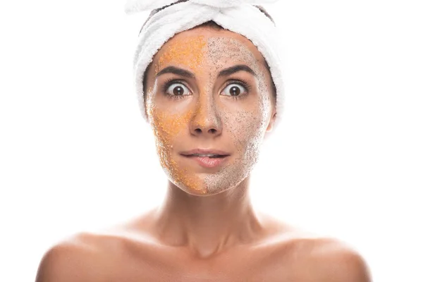 Vorderseite der schockierten jungen Frau in kosmetischen Haarband mit Peeling im Gesicht isoliert auf weiß — Stockfoto