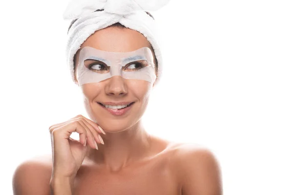 Vista frontale di giovane donna nuda sorridente in fascia di capelli cosmetici con maschera facciale isolata su bianco — Foto stock