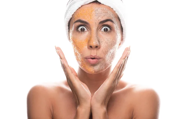 Vorderseite der schockierten jungen Frau in kosmetischen Haarband mit Peeling im Gesicht isoliert auf weiß — Stockfoto
