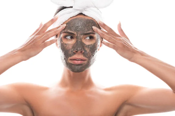 Vue de face de jeune femme nue coûteuse en bande capillaire cosmétique avec masque en argile sur le visage isolé sur blanc — Photo de stock