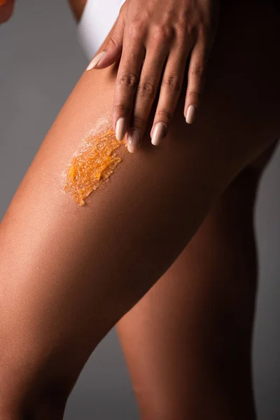 Partial view of sexy young woman applying scrub on body isolated on grey — Stock Photo