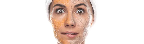Plan panoramique de femme choquée en bande capillaire cosmétique avec gommage sur le visage isolé sur blanc — Photo de stock