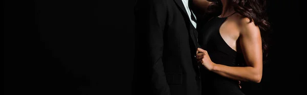 Панорамний знімок жінки торкається костюма чоловіка ізольовано на чорному — стокове фото