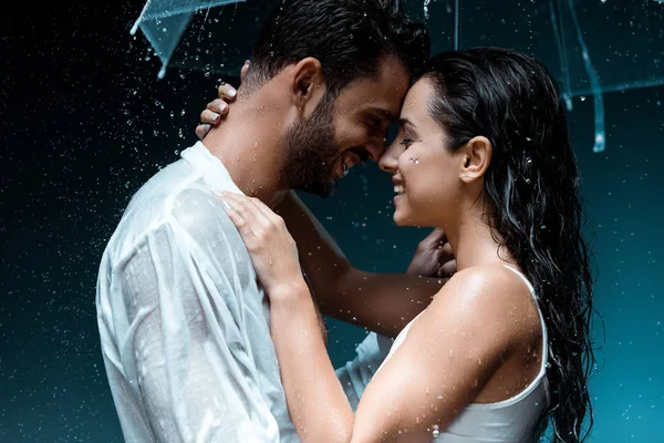 Side view of positive bearded man hugging cheerful girl and holding umbrella on black — Stock Photo