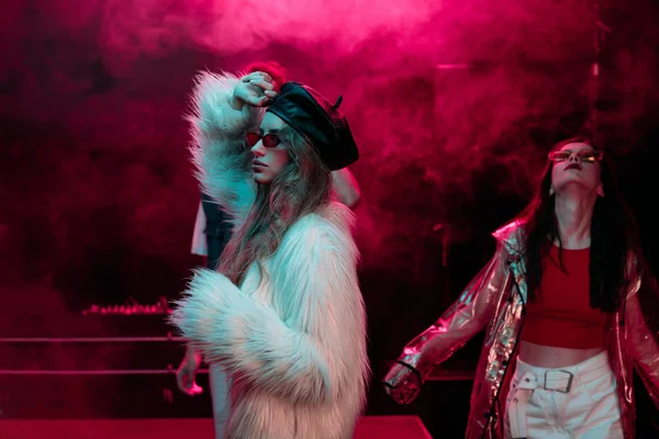 Chicas bailando en discoteca con humo rosa neón - foto de stock