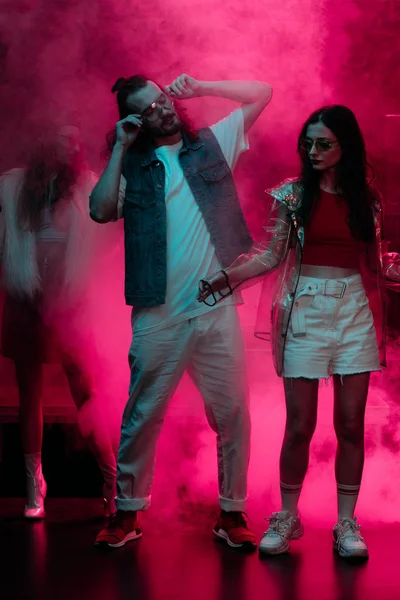 Uomo e ragazza che ballano in discoteca con neon rosa fumo — Foto stock