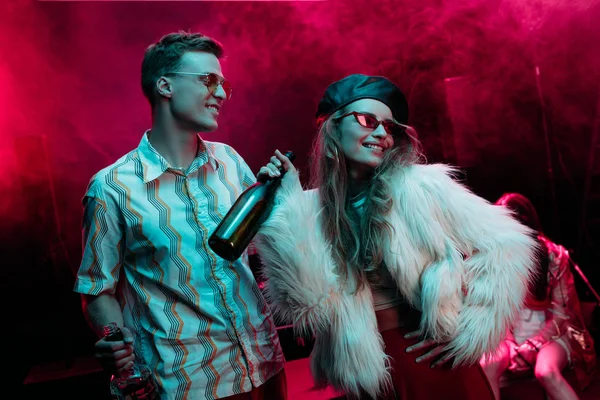 Beautiful happy young woman with beer and man in nightclub during rave — Stock Photo