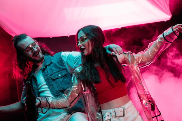 Hombre y hermosa chica bailando en discoteca con humo rosa - foto de stock