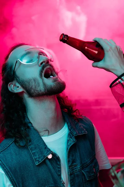 Женщина наливает алкоголь в рот мужчины в солнцезащитных очках с lsd на языке в ночном клубе — стоковое фото