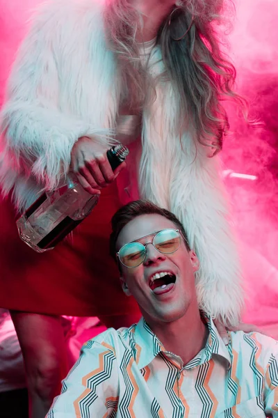 Девушка с алкоголем рядом с мужчиной в солнцезащитных очках с lsd на языке в ночном клубе — стоковое фото