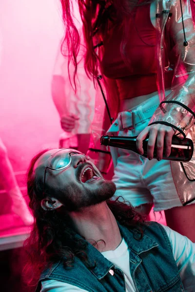 Woman pouring beer in mouth of man with lsd pill on tongue in nightclub during rave — Stock Photo