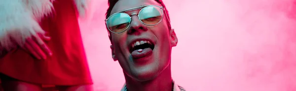 Plano panorámico de hombre con lsd en lengua en discoteca con humo rosa - foto de stock