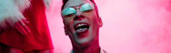 Tiro panorâmico de homem com lsd na língua em boate com fumaça rosa — Fotografia de Stock
