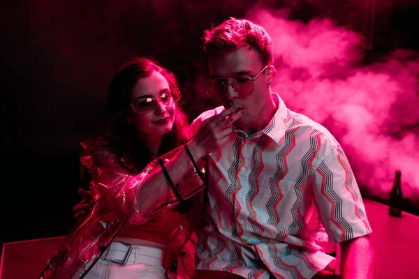 Uomo fumare sigaretta vicino alla giovane donna durante la festa rave in discoteca — Foto stock