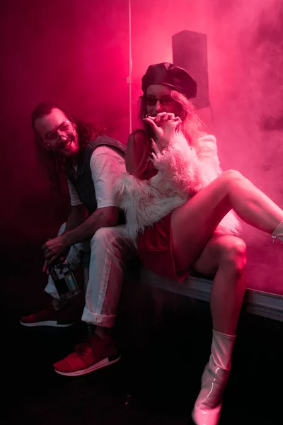 Junge Frau mit Zigarette sitzt bei Rave-Party in Nachtclub neben Mann — Stockfoto