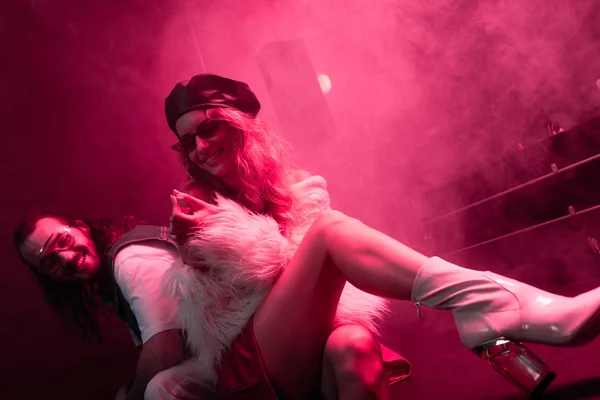 Young woman with cigarette sitting near man during rave party in nightclub — Stock Photo