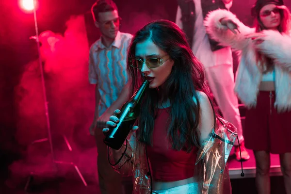 Schöne Mädchen mit Sonnenbrille trinkt Bier in Nachtclub während Rave — Stockfoto
